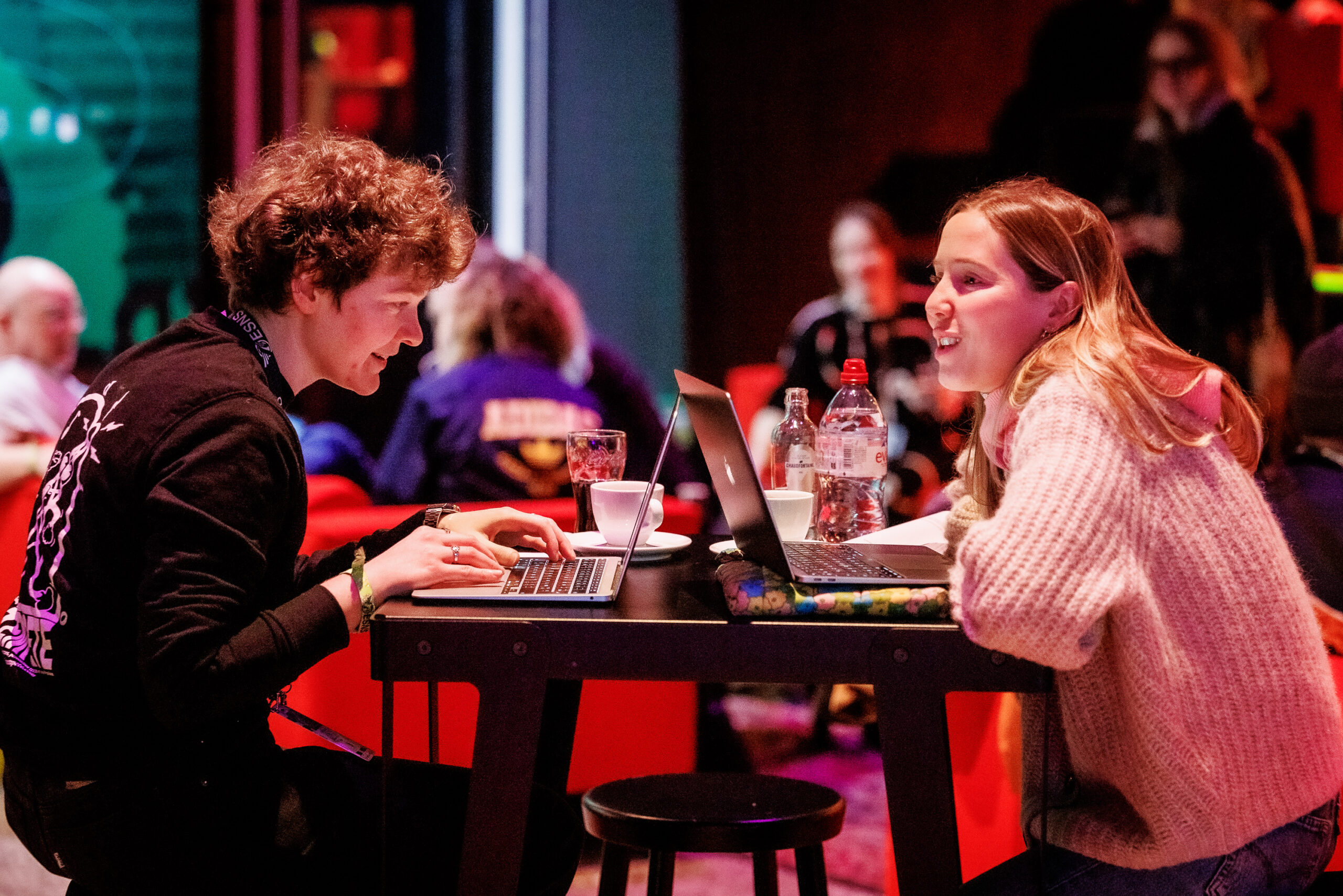 Deux festivaliers de ESNS face à face semblent discuter, ils sont sur leurs ordinateurs